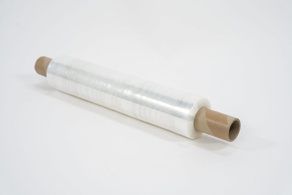 A roll of Pallet Wrap – Clear with brown cardboard tubes at both ends is placed diagonally on a white surface.