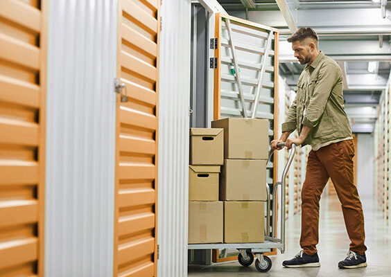 Man moving into his storage unit with boxes and a trolley