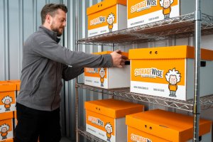 person placing a box of files onto storage shelves