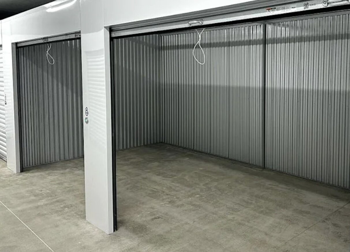 Why More Irish Entrepreneurs Are Ditching Home Working for Dedicated Office Space in Limerick 1 Two empty indoor storage units with raised metal roller doors, situated next to each other, featuring concrete floors and corrugated metal walls—ideal for home working or as affordable office space in Limerick entrepreneurs can adapt to their needs.